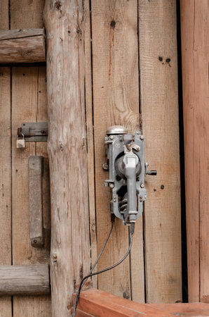 An old telephone with a disk hangs on a wooden door.の写真素材