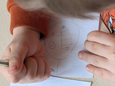 The child draws pictures on the table, shot in close-up.
