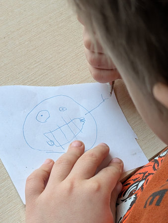 The child draws pictures on the table, shot in close-up.