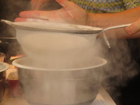 close up on chef hands sifting flourの写真素材