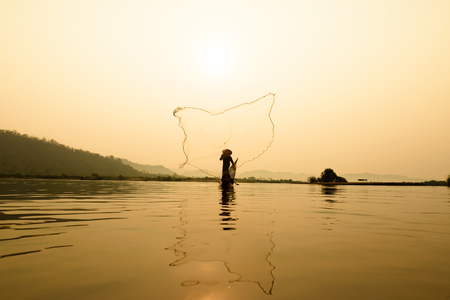 fisherman on boat with sunrise background, the Mekong River in Thailandの写真素材