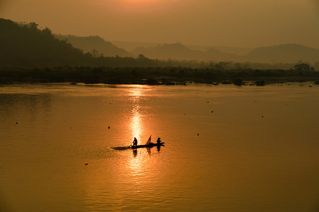 fisherman on boat with sunrise background, the Mekong River in Thailandの写真素材