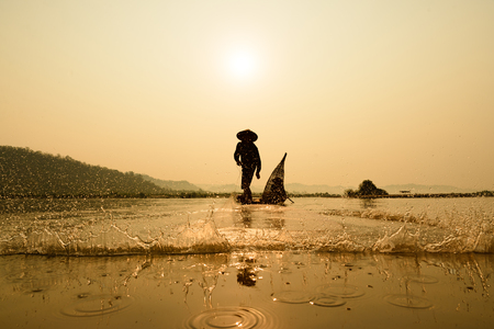 fisherman on boat with sunrise background, the Mekong River in Thailandの写真素材