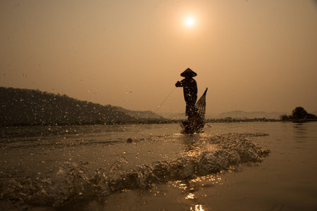 fisherman on boat with sunrise background, the Mekong River in Thailandの写真素材