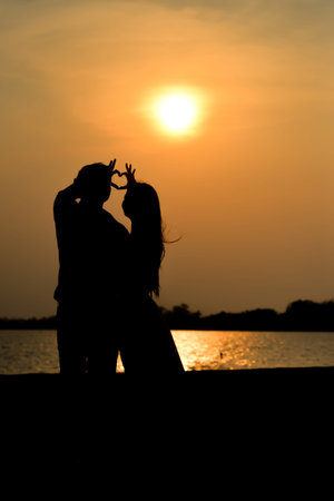 Couple make hand heart symbol shaped with beautiful sunset  nature on backgroundの写真素材