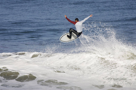 surfeur executing an aerial on the top of the wave