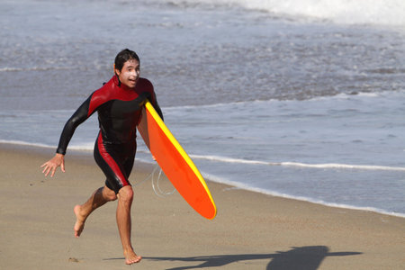 surfer running on the beach の写真素材