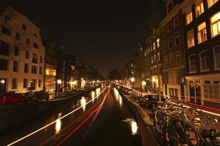 Night city view along a canal in the center of Amsterdam, the Netherlands, with headlight tracks from cars and boatsのeditorial素材