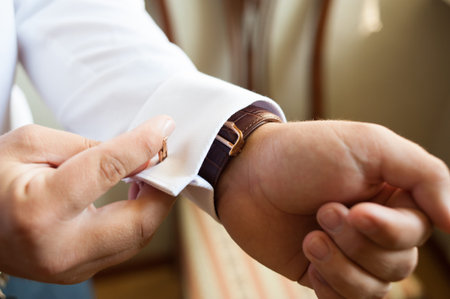Groom fastening a cufflink
