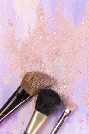 Makeup brushes on a light purple watercolor background, with traces of powder and blush on it. A vertical template for a makeup artist's business card designの写真素材