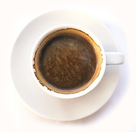 A photo of black coffee in a white cup, shot from above on a white background. Selective focus on the rim of the cupの写真素材