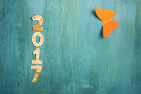 Photo of numbers forming '2017', cut out of paper with golden and white paint strokes, shot from above on vibrant turquoise background, with paper butterfly. New Year greeting cardの写真素材