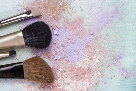 Makeup brushes on a teal blue background, with traces of powder and blush on it. A horizontal template for a makeup artist's business card designの写真素材