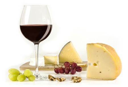 A photo of a tasting with a glass of red wine, different types of cheese, nuts, and grapes, on a white backgroundの写真素材