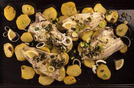 A photo of a sea bream, baked in the oven with potatoes and onions. A traditional Madrid recipeの写真素材