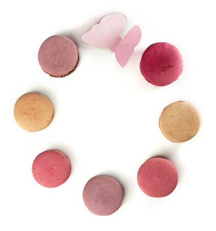 A photo of various pastel coloured macarons and a paper butterfly, shot from above, forming a frame on a white backgroundの写真素材