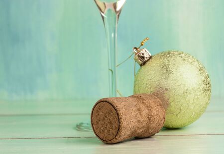 A photo of a sparkling wine cork with a blurred Christmas tree ball and a glass stem in the background. Selective focus and copyspaceの写真素材