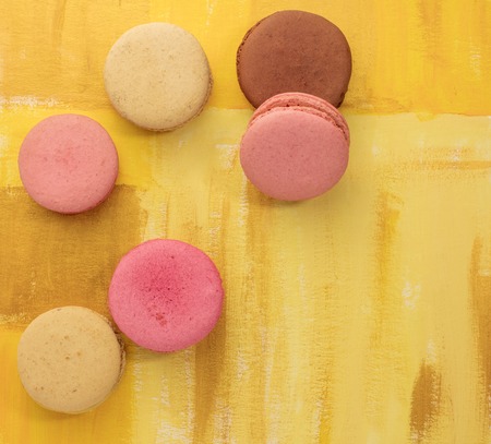 A photo of vibrant macarons, shot from above on a bright yellow background texture, with copyspaceの写真素材