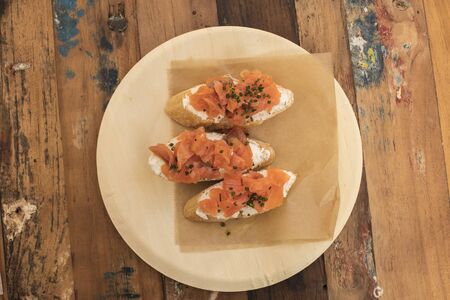 Salmon sandwiches, served as tapas in a bar, shot from above on a wooden table with copyspaceの写真素材