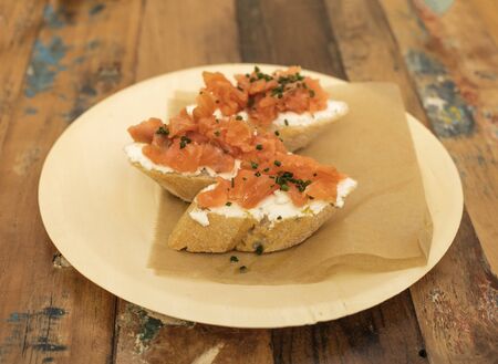Salmon sandwiches, served as tapas in a bar, shot on a wooden table with copyspaceの写真素材