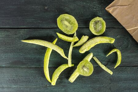A photo of dried fruits fallen out of a kraft paper bag on a dark wooden boards texture with copyspaceの写真素材