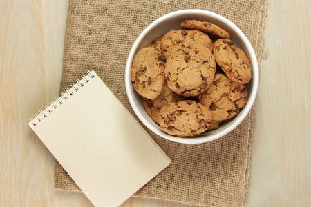 Chocolate chips cookies in bowl with notepad for copyspaceの写真素材
