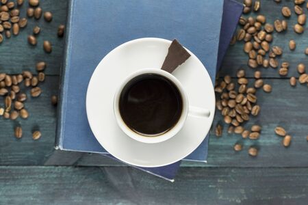 Coffee cup with old books, chocolate piece and grainsの写真素材
