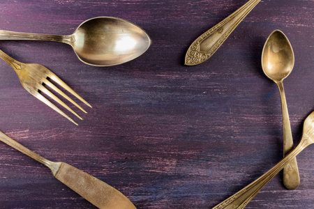 Vintage forks, knife, and spoons, forming frame on purple