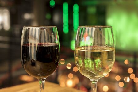 Red and white wine glasses on blurred lights backgroundの写真素材
