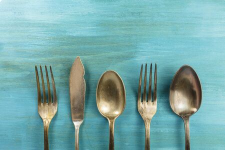 Vintage forks, knife, and spoons, forming frame on turquoiseの写真素材