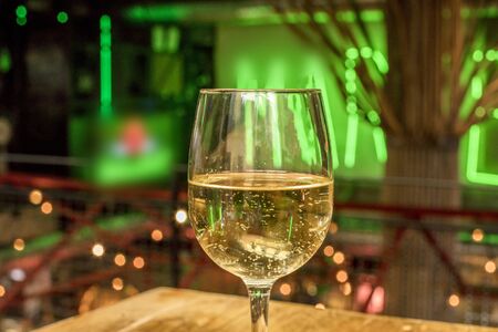 Glass of white wine on blurred lights backgroundの写真素材
