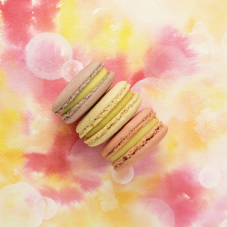 Tender pastel macarons on pink watercolor texture with copyspaceの写真素材