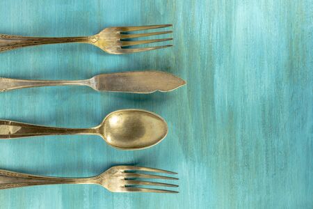 Vintage forks, knife, and spoons, forming frame on turquoiseの写真素材