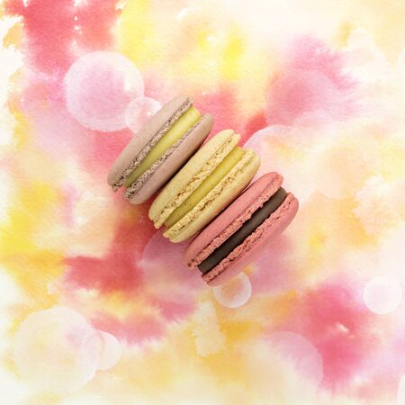 Tender pastel macarons on pink watercolor texture with copyspaceの写真素材