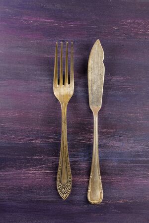 Vintage fork and knife on purple with copyspaceの写真素材