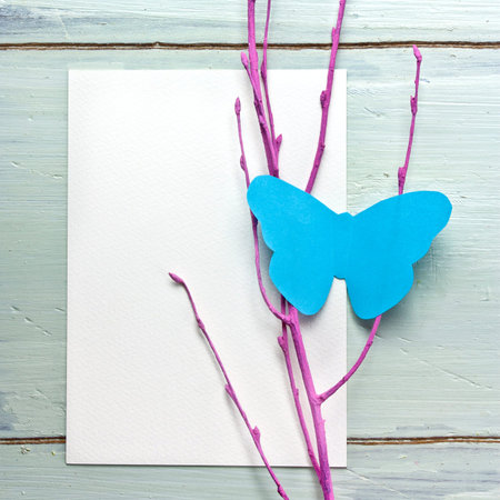 Blue paper butterfly on pink branch, with white cardの写真素材
