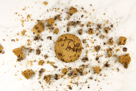 Chocolate chips cookie with crumbs on white marbleの写真素材