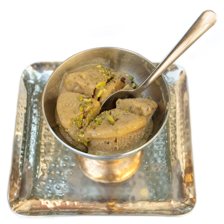A photo of kulfi, traditional Indian ice cream, in a typical bowl, on white background. Selective focus on the dessertの写真素材