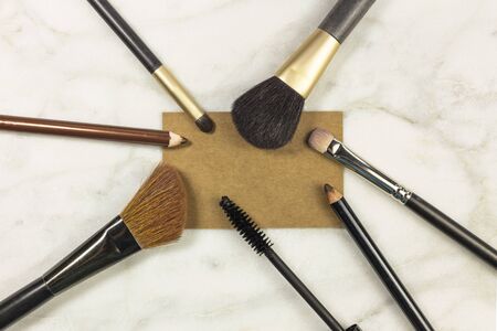 Makeup brushes and pencils on a light background, with a blank business card for copy space. A horizontal template for a makeup artist's business card or flyer designの写真素材
