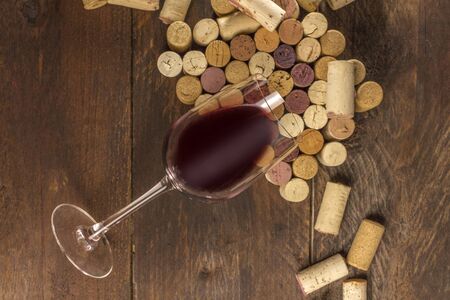 Glass of red wine and corks on dark backgroundの写真素材