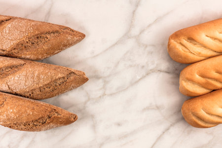 Loaves of rye and wheat bread on white marble