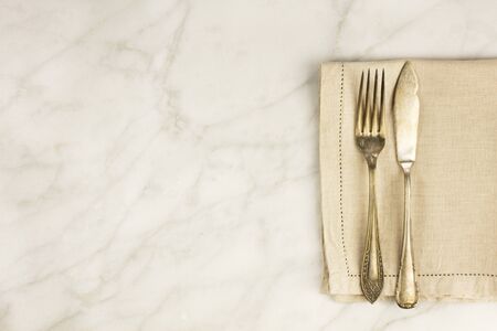 Vintage fork and knife on white marble table with copyspaceの写真素材