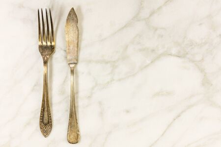Vintage fork and fish knife on white marble with copyspaceの写真素材