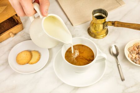 Milk poured into cup of coffeeの写真素材
