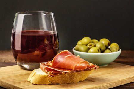 Jamon tapa, cured ham on bread with wineの写真素材