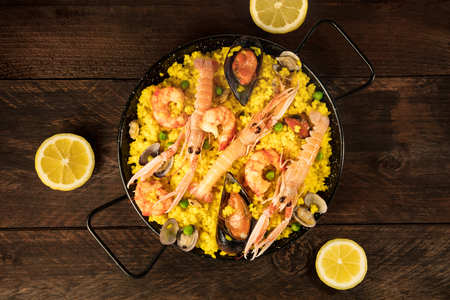 Spanish seafood paella in paellera, with lemonsの写真素材