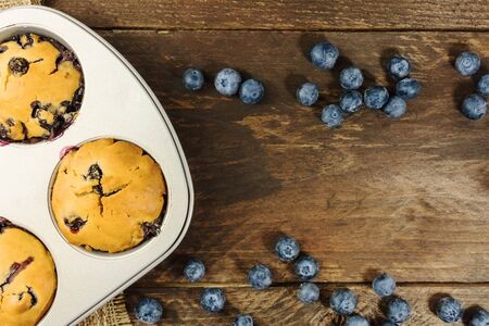 Freshly baked muffins and blueberries on rustic textureの写真素材