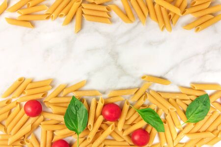 Penne rigate, cherry tomatoes, and basil leaves with copyspaceの写真素材