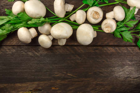 Overhead photo of white mushrooms with green parsley leavesの写真素材