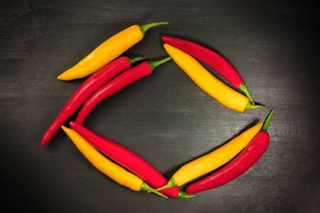 Red and yellow chili peppers forming frame on blackの写真素材